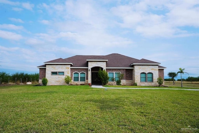 20985 Espinoza Rd, San Benito, TX 78586 - view of front facade with stone siding, a front lawn, brick siding, and roof with shingles