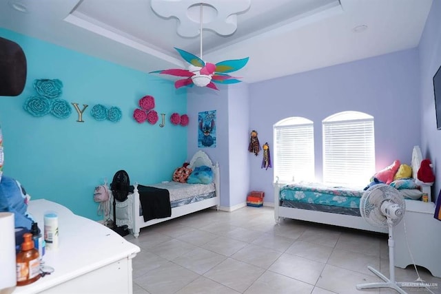 bedroom with a tray ceiling, tile patterned floors, and ceiling fan