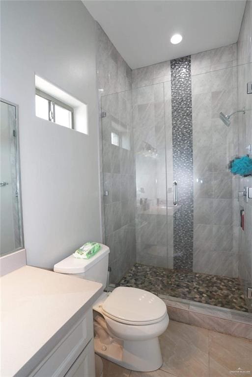 bathroom with tile patterned floors, vanity, toilet, and a shower with shower door