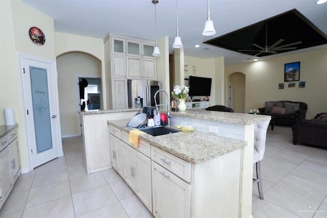 kitchen featuring a center island with sink, white cabinets, decorative light fixtures, and stainless steel refrigerator with ice dispenser