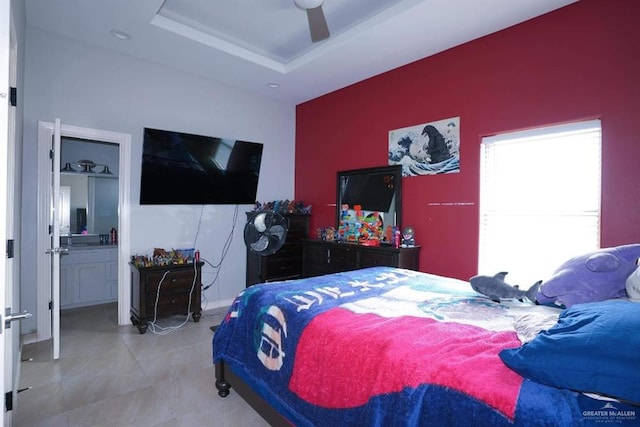 bedroom featuring a tray ceiling, connected bathroom, and ceiling fan