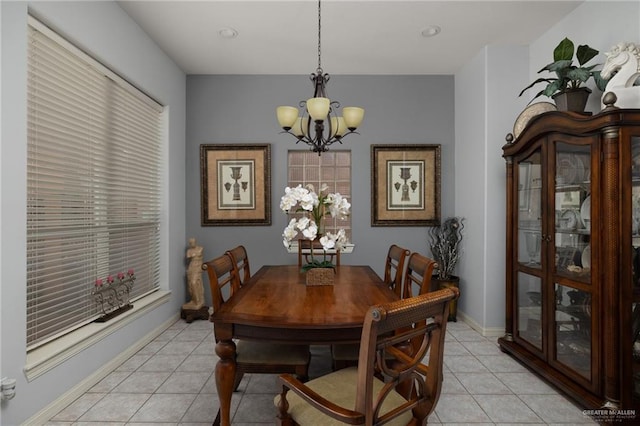 dining space with an inviting chandelier, light tile patterned floors, and baseboards