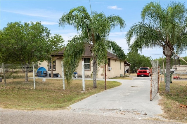 view of front of house with cooling unit, fence, concrete driveway, stucco siding, and a front yard