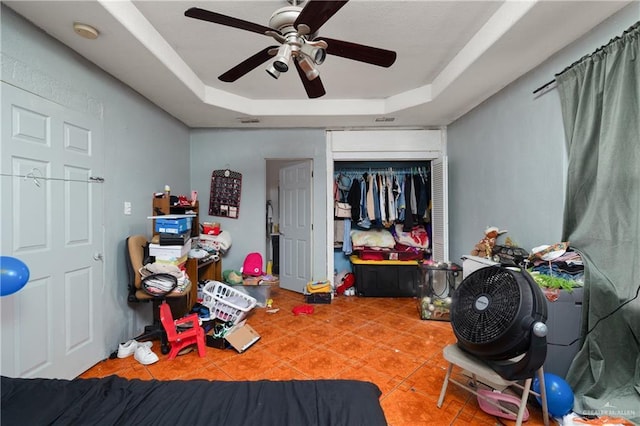 tiled bedroom with ceiling fan, a closet, a raised ceiling, and visible vents