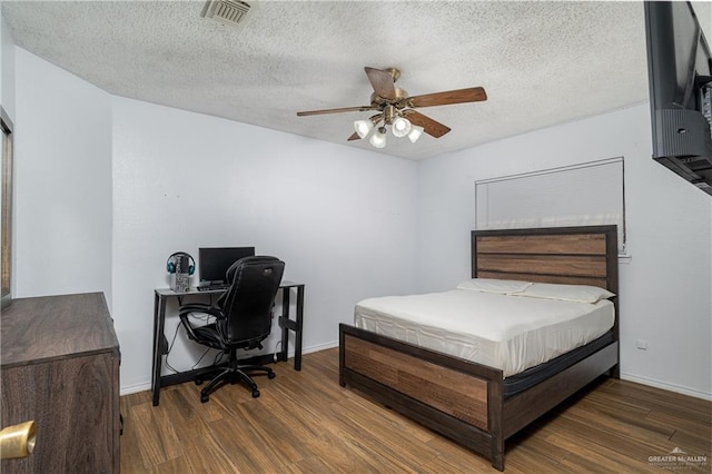 bedroom featuring ceiling fan, dark hardwood / wood-style floors, and a textured ceiling