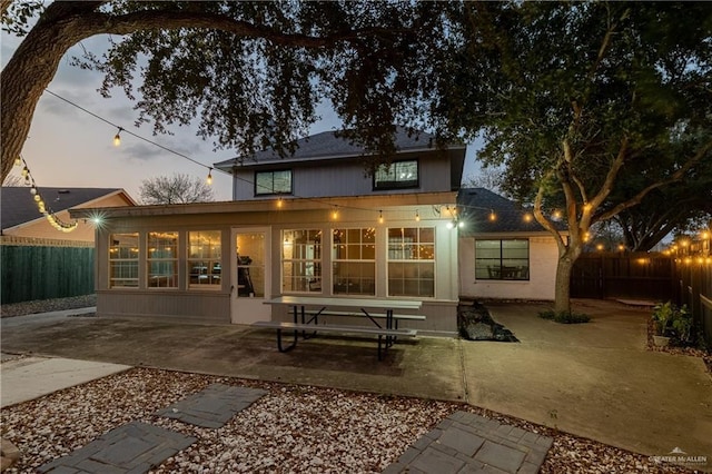 back house at dusk featuring a sunroom and a patio area