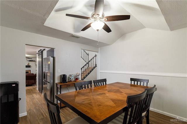 dining room with dark hardwood / wood-style flooring, ceiling fan, lofted ceiling, and a textured ceiling