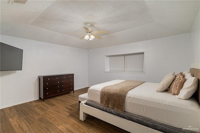 bedroom with ceiling fan, dark hardwood / wood-style floors, and a textured ceiling