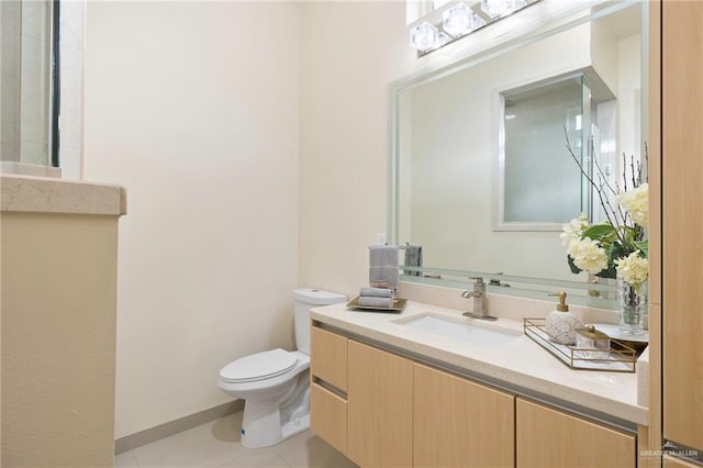 bathroom with tile patterned flooring, baseboards, vanity, and toilet