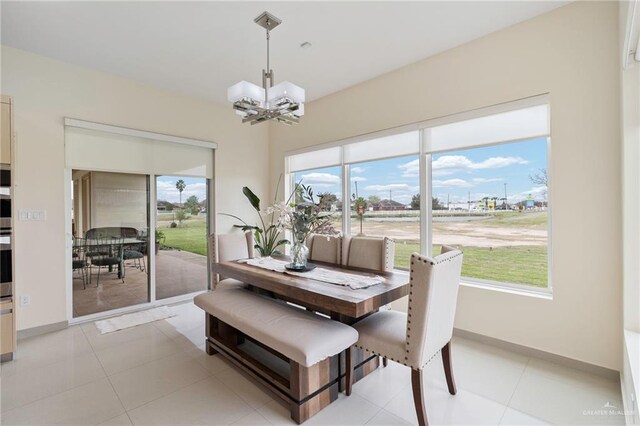 dining area with light tile patterned floors, plenty of natural light, baseboards, and an inviting chandelier