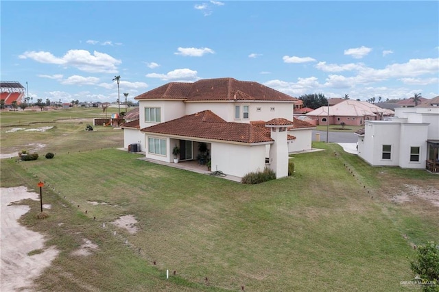 rear view of property featuring a tiled roof, a yard, cooling unit, and stucco siding