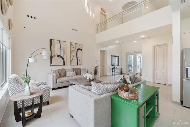 living room with french doors, a towering ceiling, and light tile patterned floors