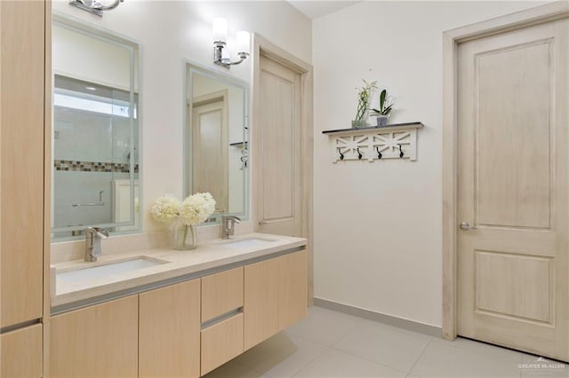 bathroom featuring double vanity, tile patterned flooring, a sink, and baseboards