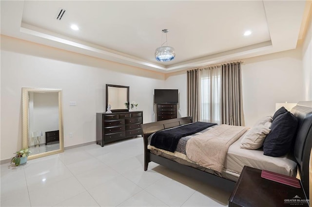 bedroom with light tile patterned floors, visible vents, a tray ceiling, and baseboards