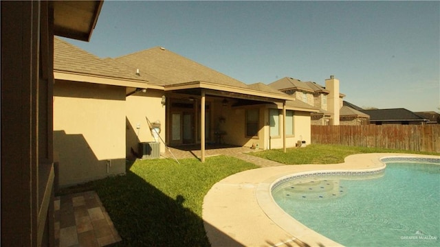 rear view of property with a fenced in pool and a lawn