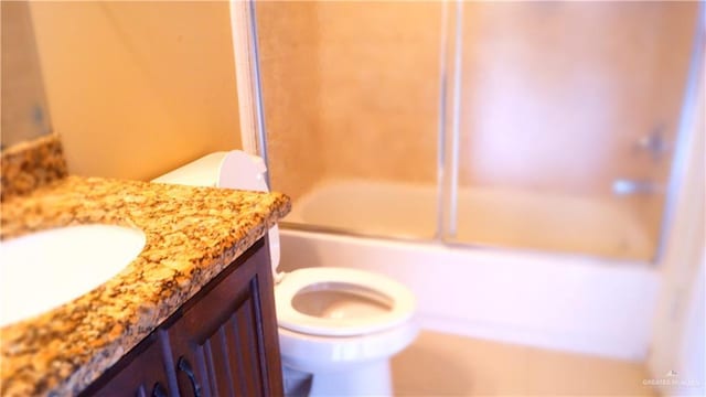 full bathroom featuring vanity, combined bath / shower with glass door, and toilet