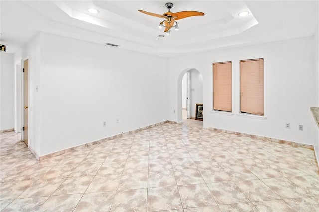 empty room featuring ceiling fan and a tray ceiling