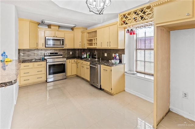 kitchen featuring decorative backsplash, sink, stainless steel appliances, and a chandelier