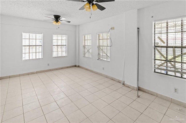 empty room featuring ceiling fan, light tile patterned floors, and a textured ceiling