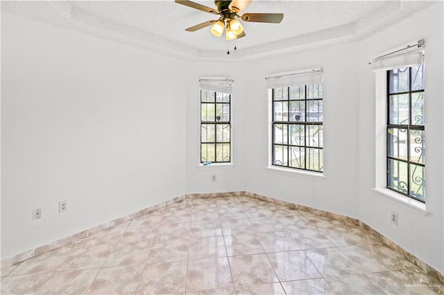 spare room with light tile patterned floors, a textured ceiling, a raised ceiling, and ceiling fan