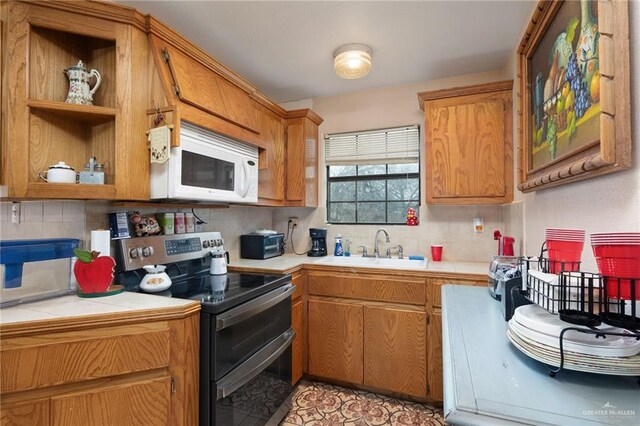 kitchen with decorative backsplash, sink, tile counters, and electric stove