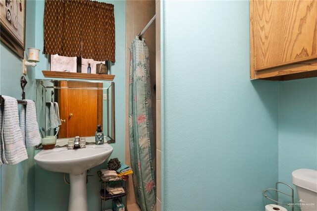 bathroom with sink, a shower with shower curtain, and toilet