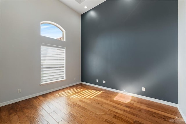 unfurnished room with hardwood / wood-style flooring and a high ceiling