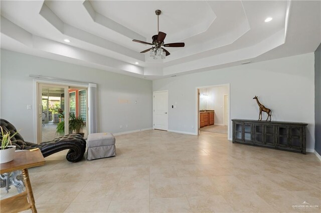 living area with a tray ceiling and ceiling fan