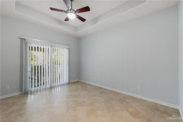 unfurnished room with light tile patterned floors, a tray ceiling, and ceiling fan