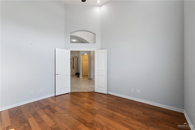 empty room with hardwood / wood-style floors and a high ceiling