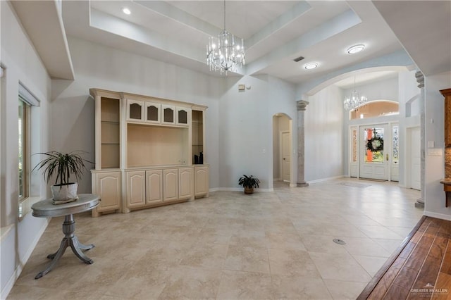 entrance foyer featuring a raised ceiling, a high ceiling, and an inviting chandelier