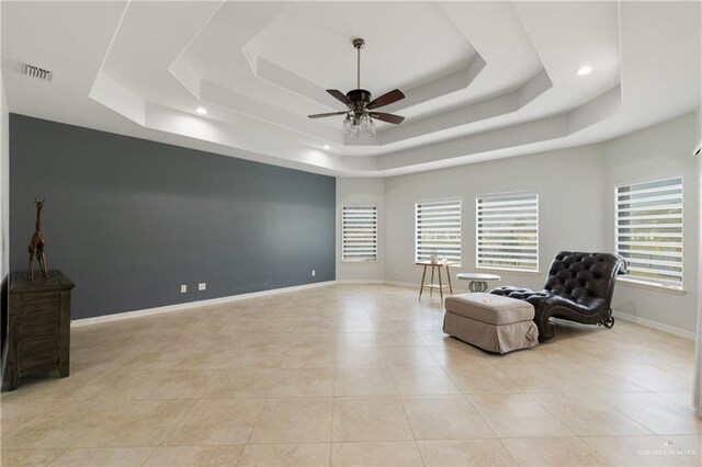 living area featuring light tile patterned floors, a raised ceiling, and ceiling fan