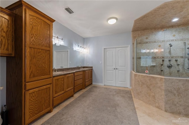 bathroom with tiled shower, vanity, and tile patterned flooring