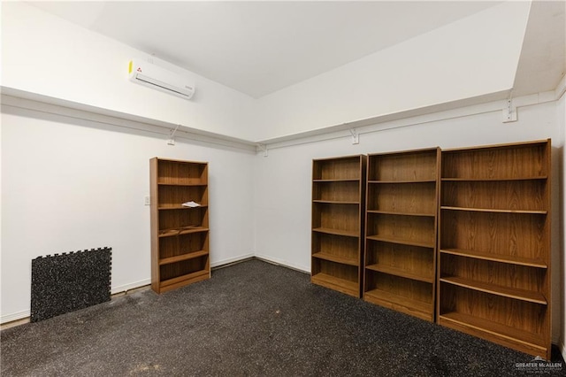 spacious closet with a wall mounted air conditioner and dark carpet