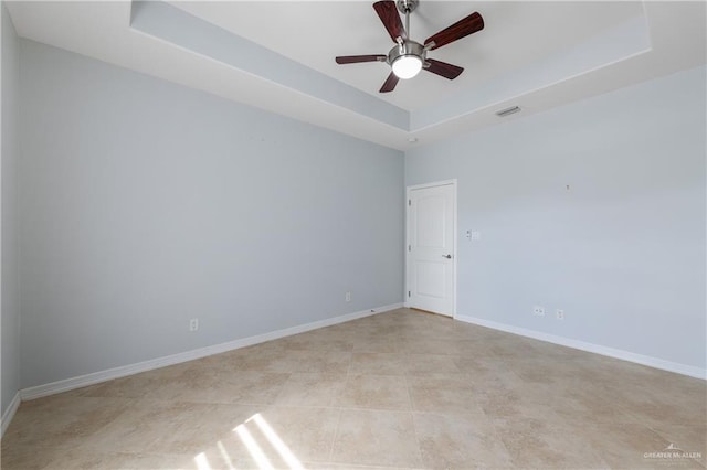 unfurnished room with ceiling fan and a raised ceiling