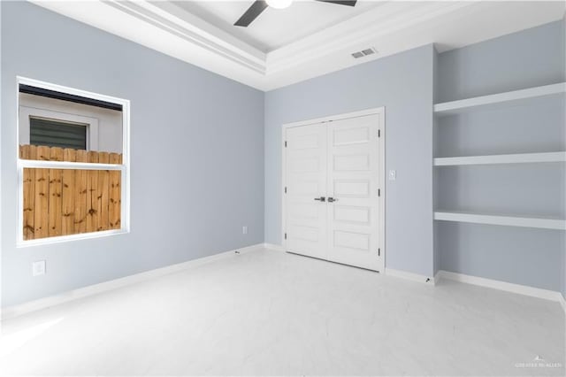 unfurnished bedroom featuring a tray ceiling, a closet, and ceiling fan