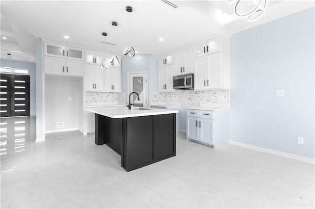 kitchen with white cabinetry, sink, hanging light fixtures, and an island with sink