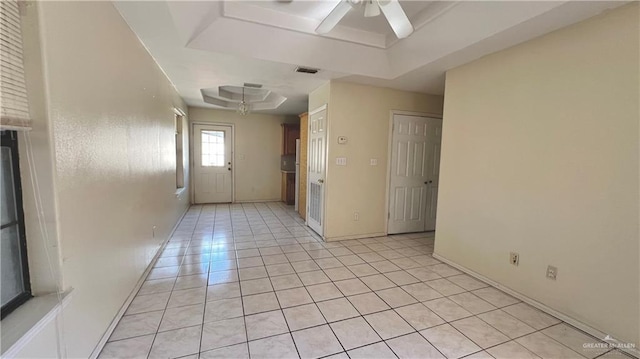 tiled spare room featuring a tray ceiling and ceiling fan