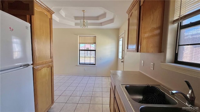 kitchen featuring light tile patterned flooring, white refrigerator, a tray ceiling, and sink