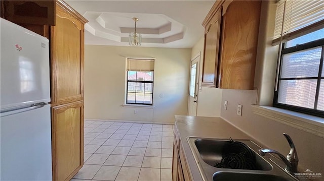 kitchen featuring sink, an inviting chandelier, white fridge, a tray ceiling, and light tile patterned flooring