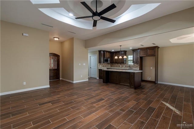 kitchen featuring wood finish floors, light countertops, visible vents, stainless steel microwave, and open floor plan