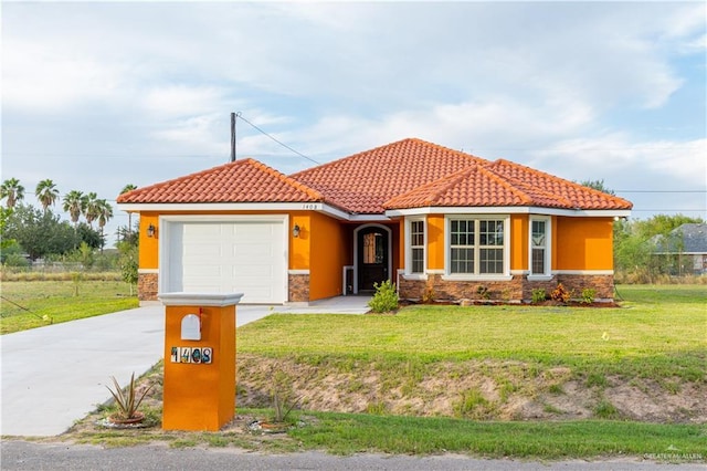 mediterranean / spanish house with a front lawn, driveway, an attached garage, and stucco siding