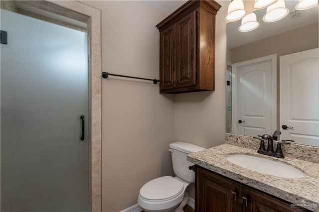 bathroom featuring a stall shower, baseboards, vanity, and toilet