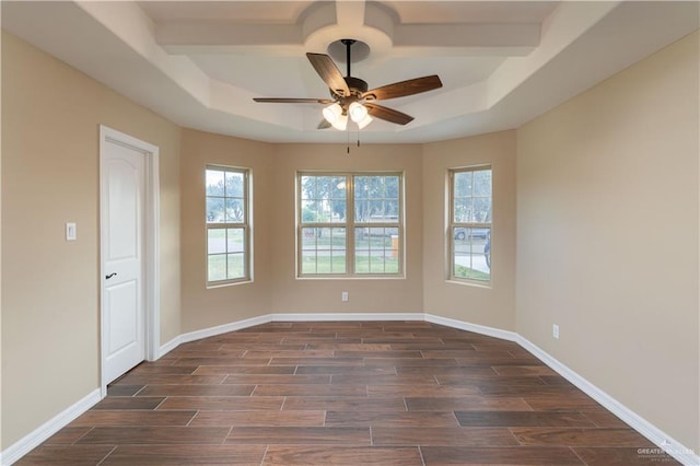 empty room featuring baseboards, a tray ceiling, and wood finish floors