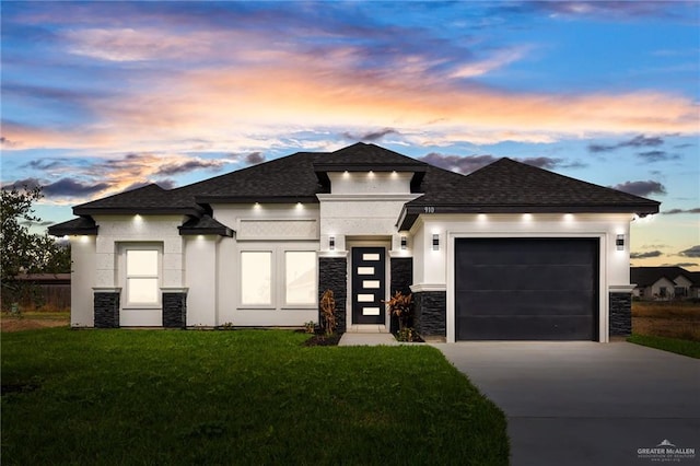 prairie-style home featuring a garage and a lawn