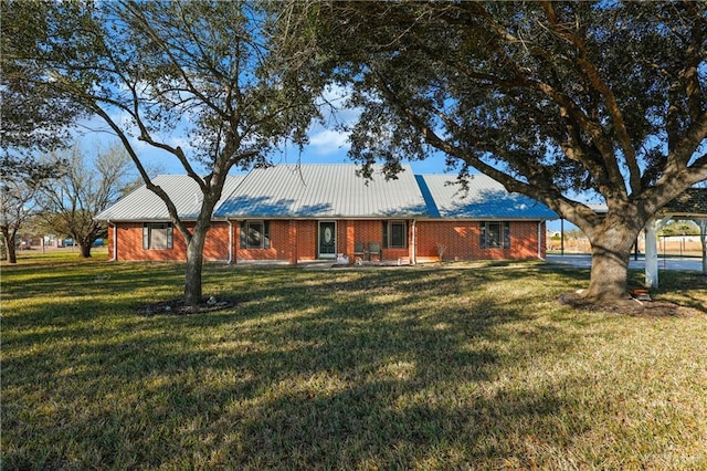 view of front facade featuring metal roof, a front lawn, and brick siding