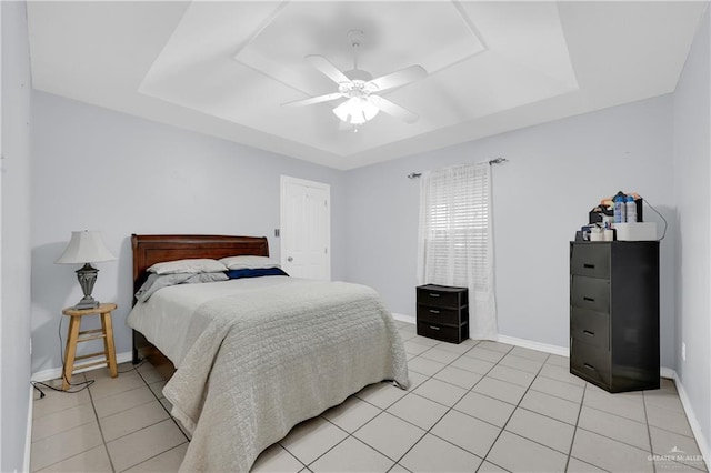 bedroom featuring light tile patterned floors, ceiling fan, a tray ceiling, and baseboards