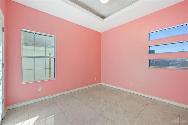 tiled spare room featuring a raised ceiling