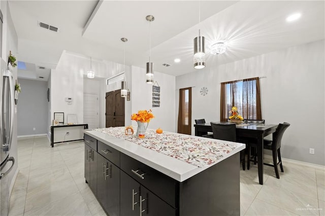 kitchen featuring stainless steel fridge, pendant lighting, and a kitchen island