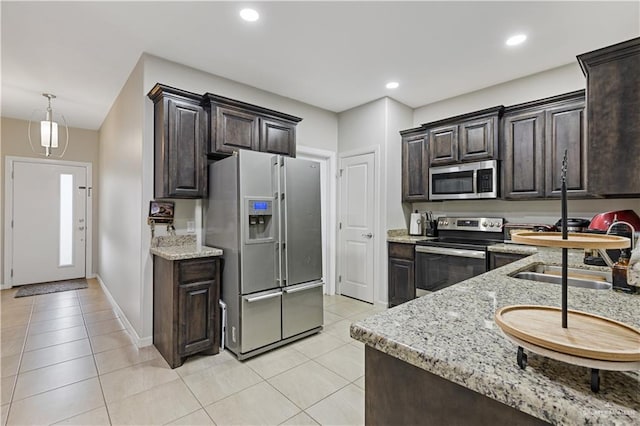 kitchen featuring light tile patterned floors, appliances with stainless steel finishes, dark brown cabinetry, and hanging light fixtures